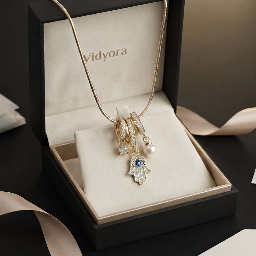 Vidyora gold-tone multi-charm necklace with Hamsa hand, pearl, and cubic zirconia pendants displayed in a luxury gift box.